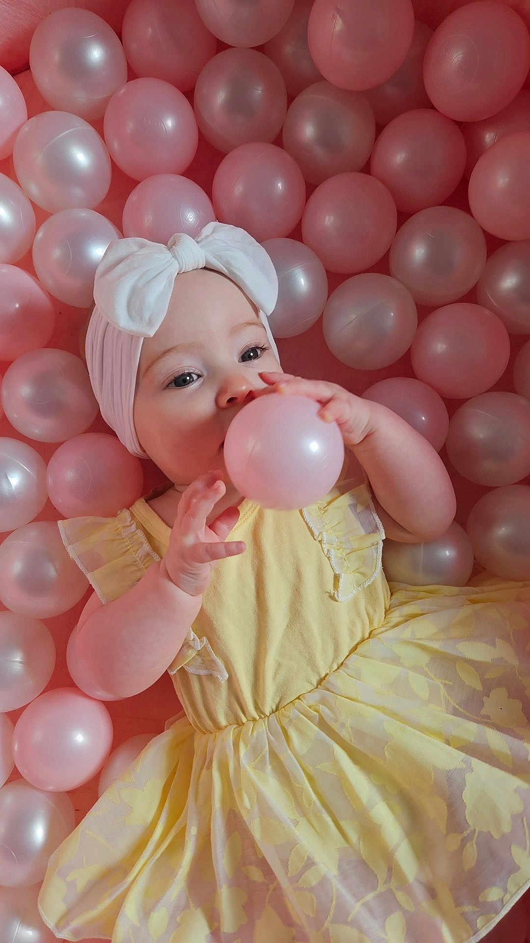 Esmée participe au concours pour gagner de l'argent avec cette photo : baby, child, yellow_dress, headband, bow, pink_balls, white_balls, playing, cute, adorable, infant, portrait, indoor, soft_lighting, hands, face, smiling, young_child, happy, fun