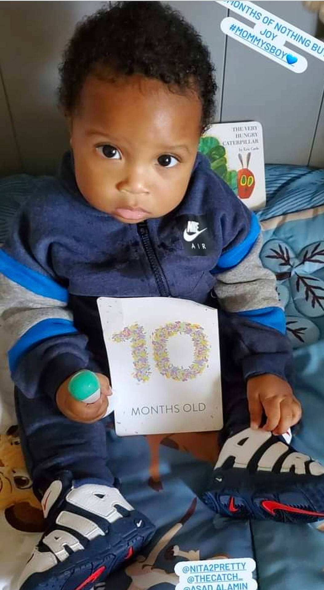 Jerry Jr is registered to the contest to win money with this photo: art, baby, baby_toddler_clothing, cheek, child, eye, finger, head, learning, organ, outerwear, pattern, person, play, reading, room, sitting, sleeve, t_shirt, thumb