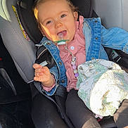 Mya a rejoint le concours — aidez-le/la à gagner de superbes lots ! child, toddler, car_seat, pacifier, denim_jacket, blanket, car_interior, smiling, happy, seatbelt, clothing, baby, face, person, sunlight, window, foot, hand, safety, cute