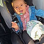 child, toddler, car_seat, pacifier, denim_jacket, blanket, car_interior, smiling, happy, seatbelt, clothing, baby, face, person, sunlight, window, foot, hand, safety, cute