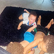 Silas is registered to the contest to win money with this photo: child, baby, play, indoor, carpet, rug, curly_hair, smile, happy, fun, toddler, clothing, barefoot, crawling, person, family, kids, floor, room, light