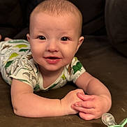 Ethan is registered to the contest to win money with this photo: baby, smiling, infant, couch, pacifier, onesie, dinosaur_pattern, hands, face, happy, indoor, blanket, furniture, child, cute, portrait, lying_down, young_child, home, cozy