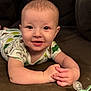 baby, smiling, infant, couch, pacifier, onesie, dinosaur_pattern, hands, face, happy, indoor, blanket, furniture, child, cute, portrait, lying_down, young_child, home, cozy