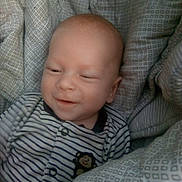 Kolton joined the competition — help win amazing prizes! baby, infant, child, striped_clothing, monkey_patch, cushion, seat, patterned_fabric, smile, sleepy, cozy, indoors, closeup, portrait, young_child, face, head, soft_lighting, comfortable, cute