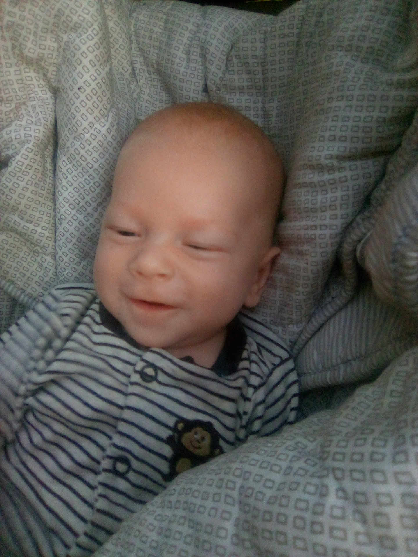 Kolton joined the competition — help win amazing prizes! baby, infant, child, striped_clothing, monkey_patch, cushion, seat, patterned_fabric, smile, sleepy, cozy, indoors, closeup, portrait, young_child, face, head, soft_lighting, comfortable, cute