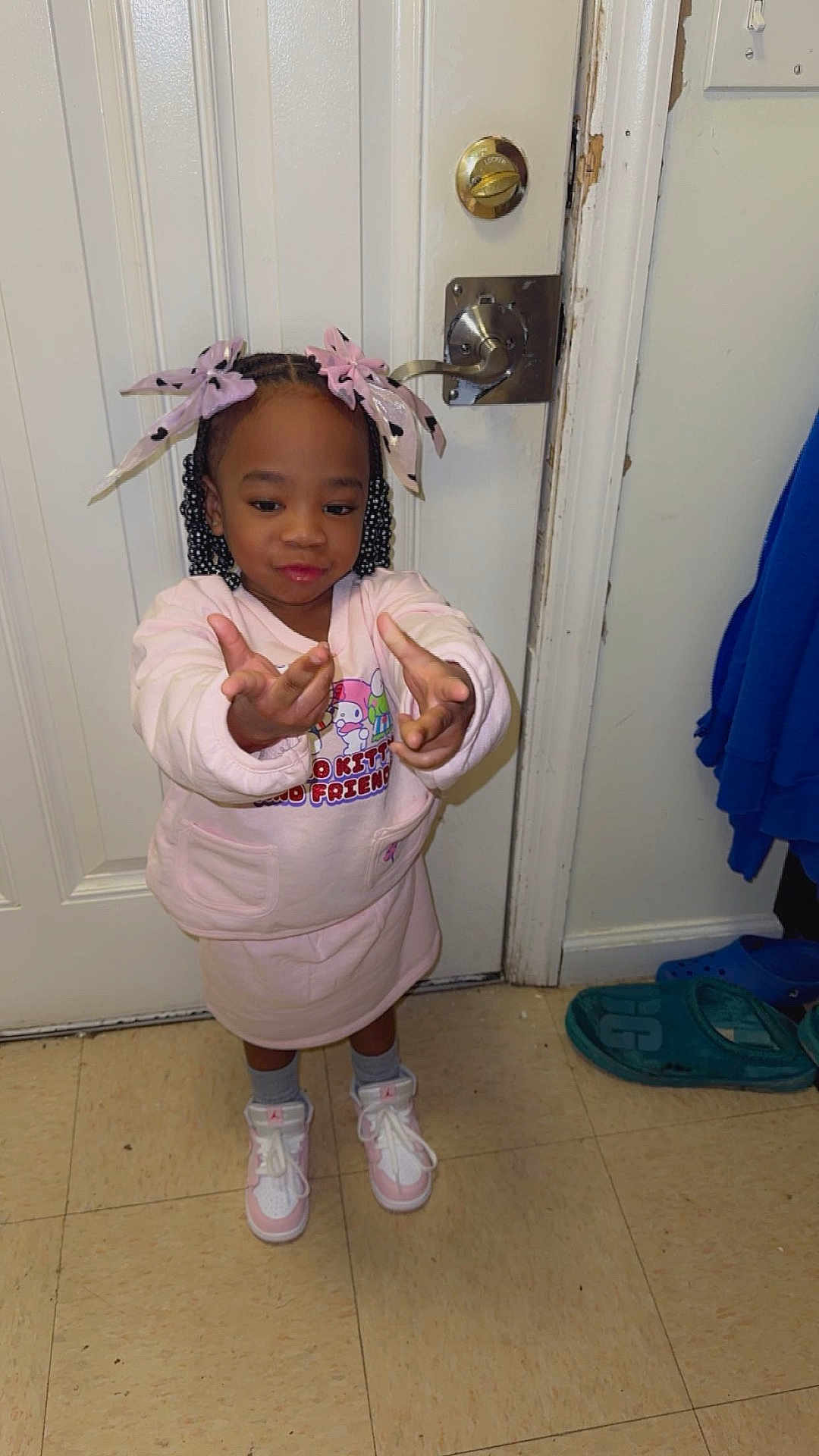 Nova joined the competition — help win amazing prizes! child, girl, braids, pink_bows, pink_outfit, sneakers, floor, door, lock, playful, pose, indoor, tiles, socks, cartoon_print, hand_gesture, smile, young_child, casual_clothing, home