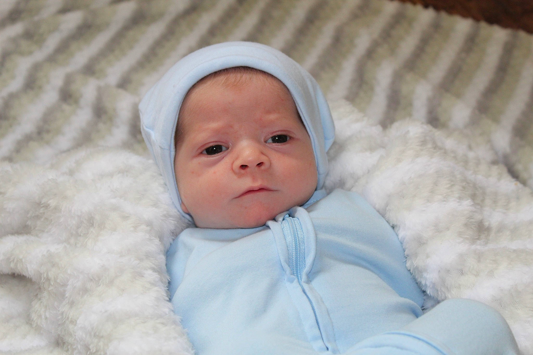 Clayton is registered to the contest to win money with this photo: baby, baby_toddler_clothing, cheek, child, comfort, event, eye, face, fur, happy, hat, headgear, linens, person, portrait_photography, room, sleeve, textile, toddler