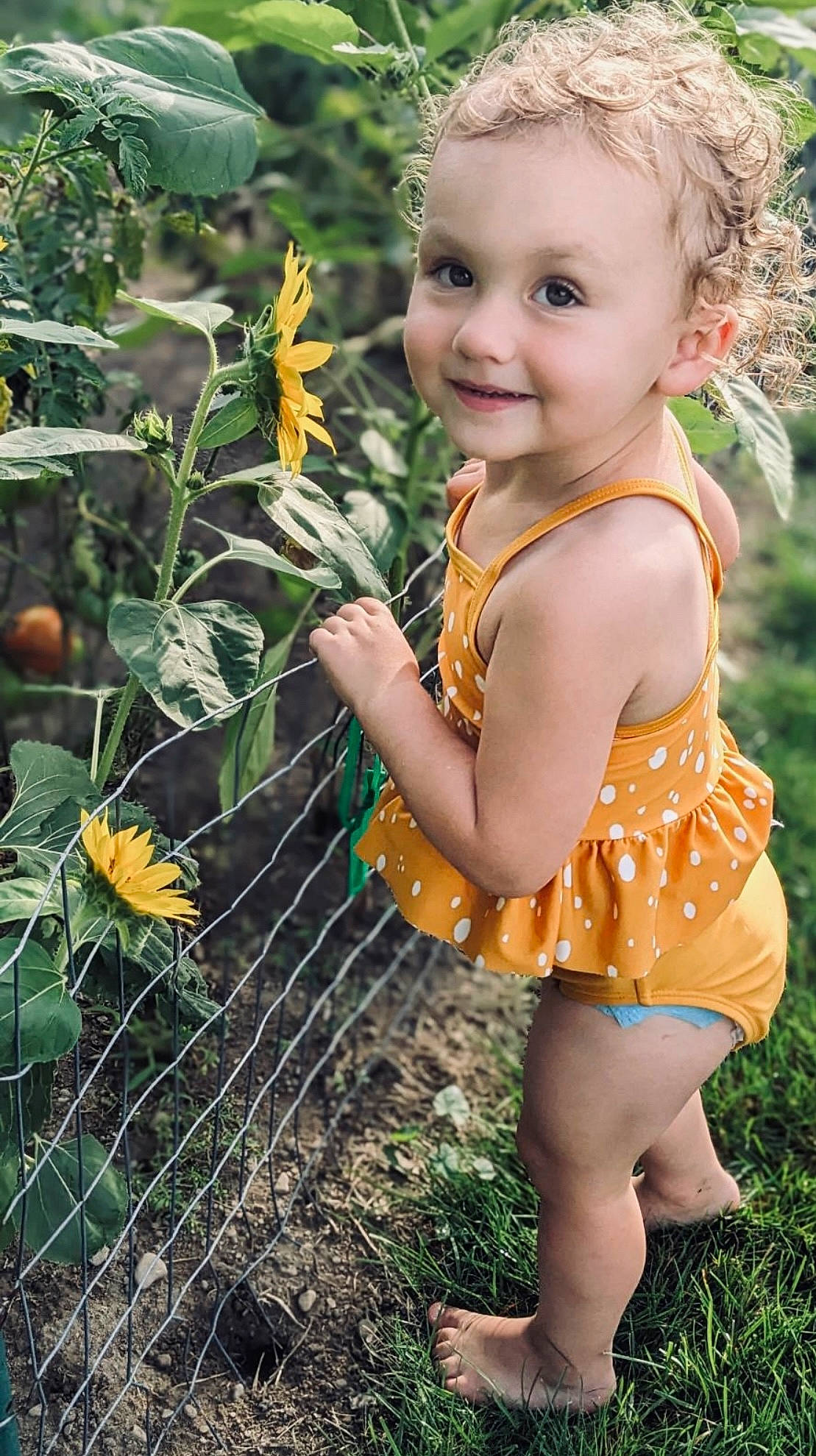Maggie is registered to the contest to win money with this photo: baby, baby_toddler_clothing, beauty, botany, child, eye, fawn, fence, flower, grass, hand, happy, iris, joy, leaf, people_in_nature, person, plant, smile, toddler