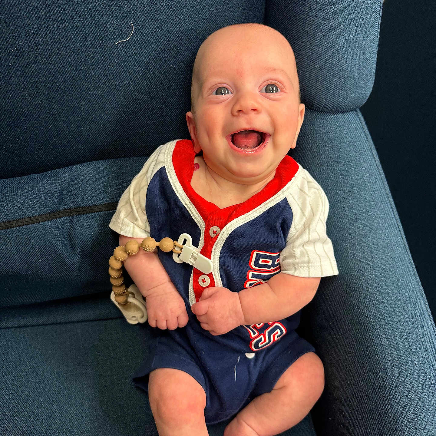 Oliver joined the competition — help win amazing prizes! baby, blue_chair, buttoned_shirt, clothing, cute, eyes, happy, head, indoors, infant, legs, mouth_open, person, portrait, short_sleeves, sitting, skin, smiling, toes, wooden_beads