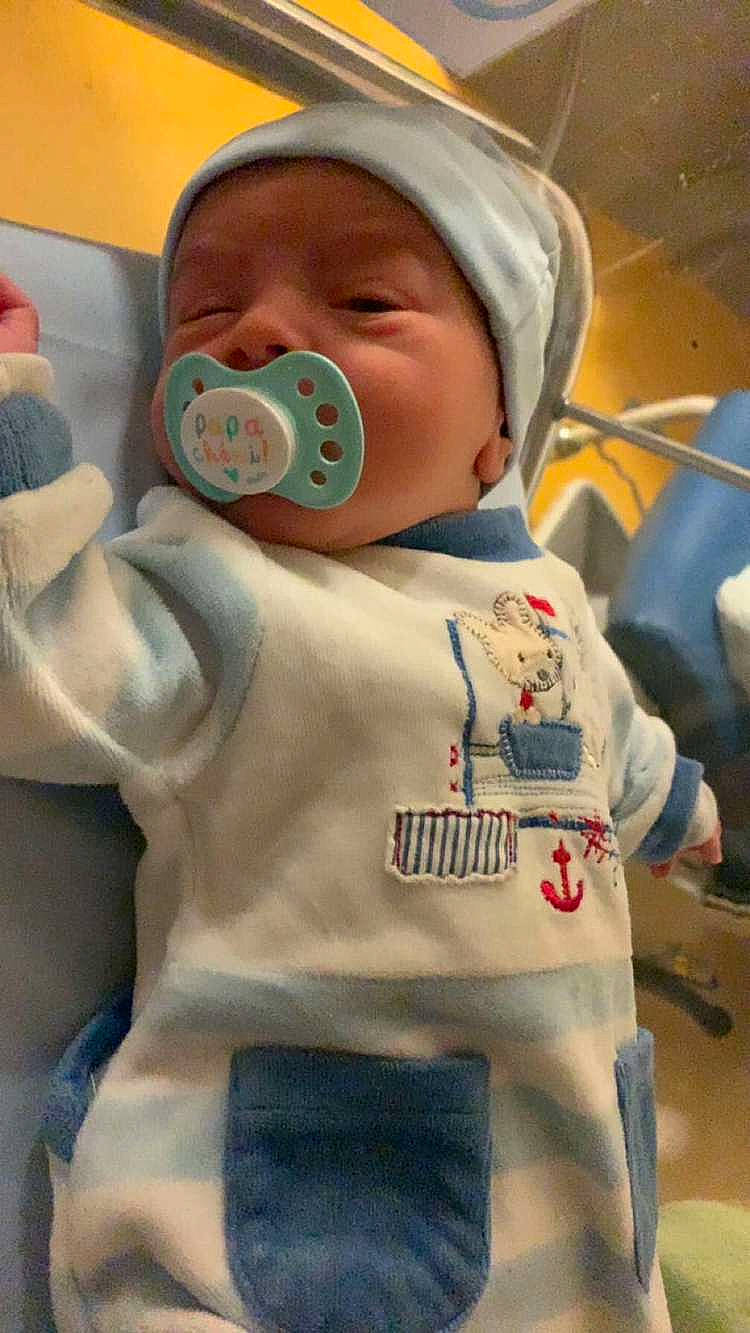 baby, bed, blanket, bonnet, clothing, coat, creditcard, face, furniture, glove, hat, head, jacket, newborn, pants, person, photography, portrait, sleeping, text