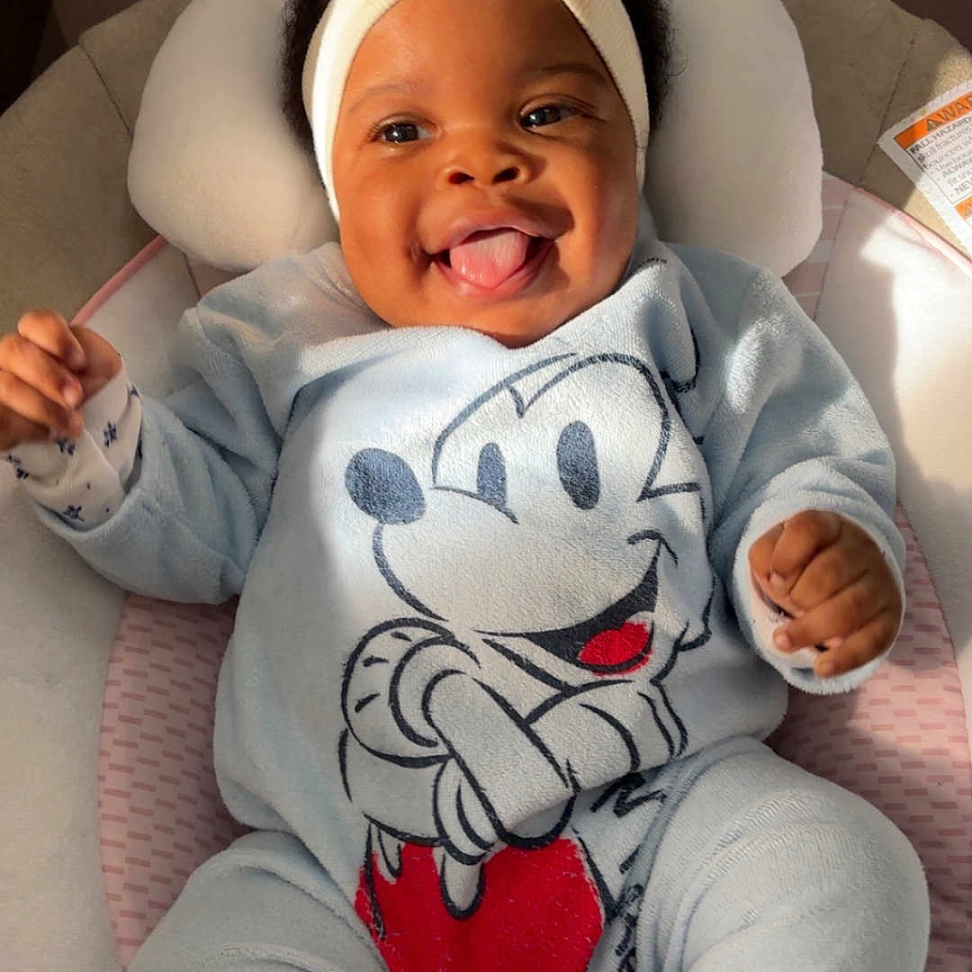 Elhyana participe au concours pour gagner de l'argent avec cette photo : baby, baby_seat, blue_clothing, child, closeup, cozy, cushion, cute, happy, headband, indoor, infant, mickey_mouse, onesie, person, playful, smile, soft_fabric, sunlight, tongue_out