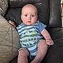 baby, infant, blue_eyes, onesie, striped_clothing, couch, leather_couch, pillow, indoor, child, cute, sitting, expression, face, skin, foot, hand, comfortable, home, portrait