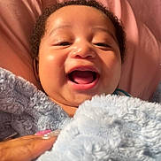 Daylin joined the competition — help win amazing prizes! baby, smiling, blanket, hand, soft_texture, happy, infant, face, curly_hair, closeup, cozy, warm_light, skin, expression, portrait, child, comfort, indoor, cute, toddler