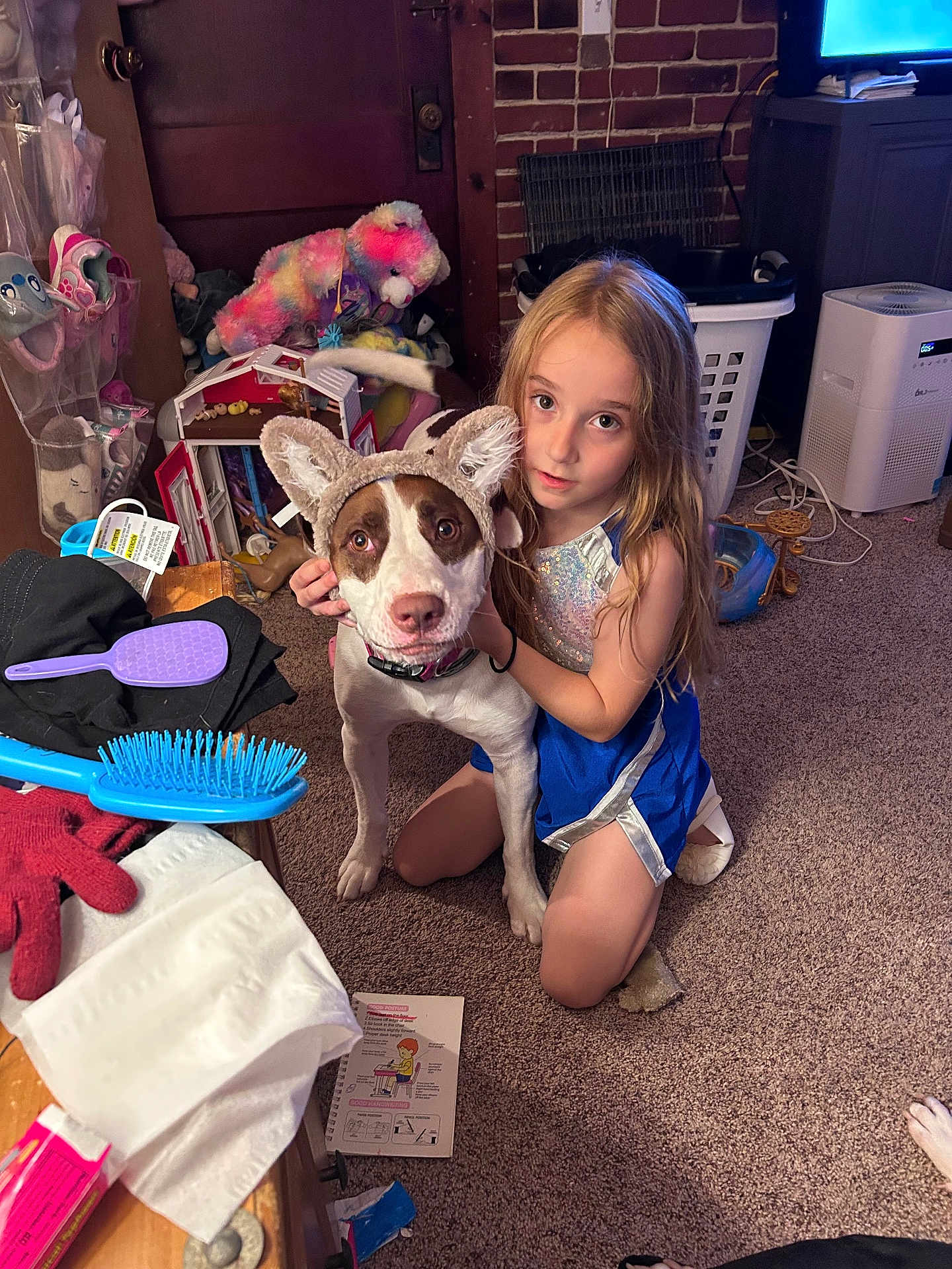 Skye joined the competition — help win amazing prizes! child, dog, indoor, carpet, toy, laundry_basket, brush, glove, headband, ears, furniture, brick_wall, door, hair_brush, clothing, pet, floor, young_girl, curly_hair, playful