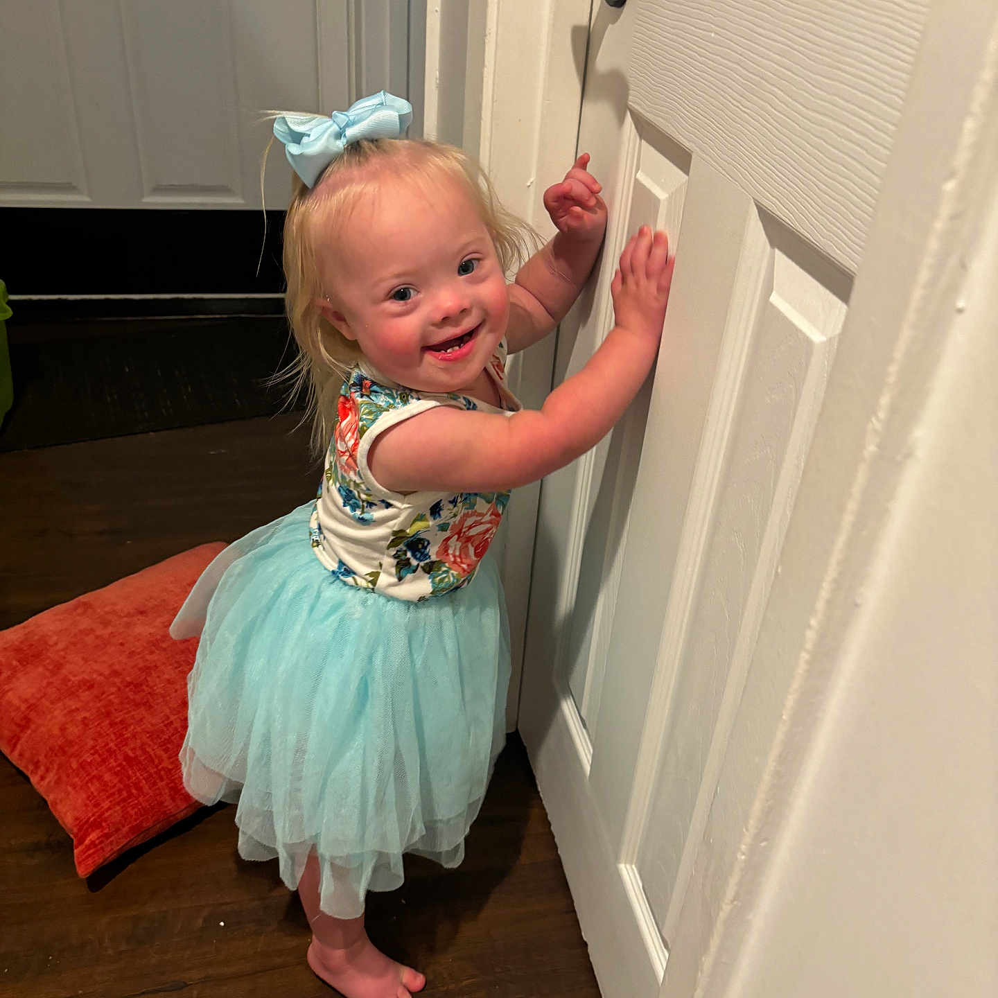 Sawyer Grace is registered to the contest to win money with this photo: barefoot, blue_bow, child, cushion, cute, door, floral_top, happy, home, indoor, light, person, playful, portrait, smiling, standing, toddler, tutu, wooden_floor, young_child