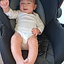 baby, black, car_seat, child, comfort, cute, foot, happy, head, indoor, infant, onesie, person, seat, skin, smiling, warning_label, waving_hand, white_clothing, young