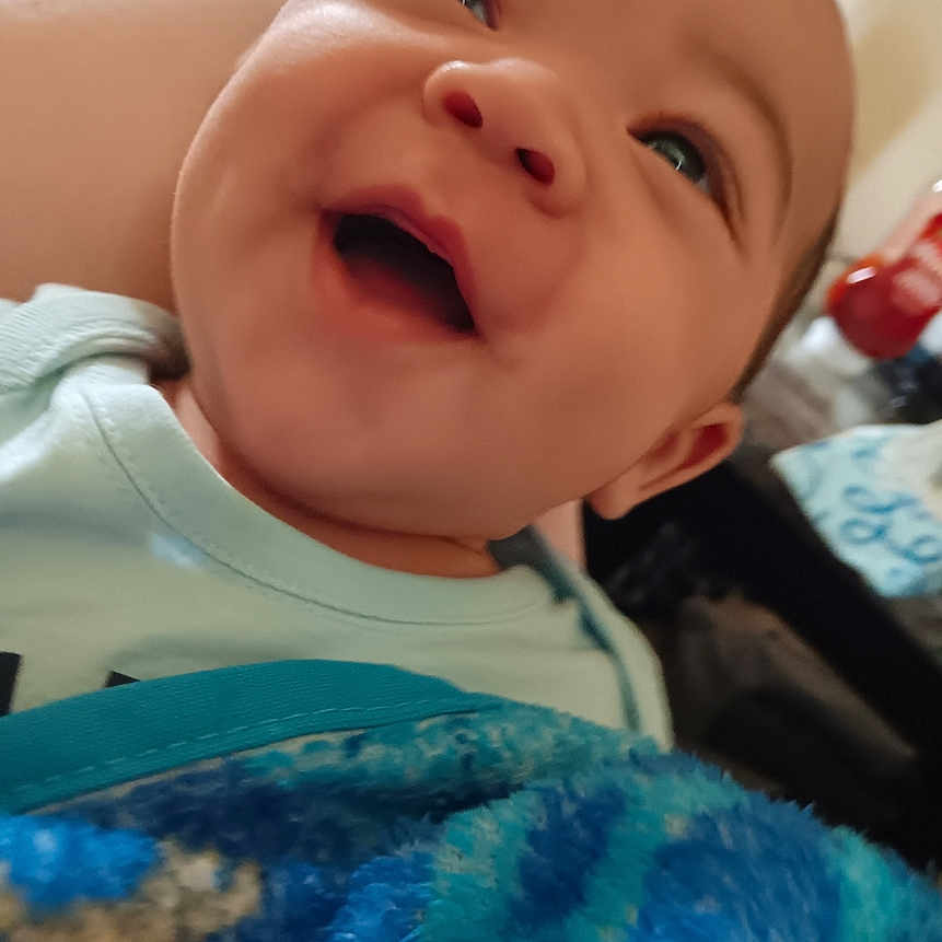 Jayvion is registered to the contest to win money with this photo: baby, blanket, child, close_up, clothing, comfort, cute, expression, face, happy, head, indoors, infant, joyful, person, portrait, skin, smiling, warmth, young