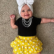 Harper is registered to the contest to win money with this photo: baby, child, smiling, headwrap, bow, black_shirt, yellow_skirt, polka_dots, carpet, infant, cute, happy, lying_down, apparel, portrait, indoors, person, chubby_cheeks, hand, feet