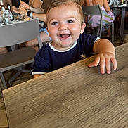 Andrea participe au concours pour gagner de l'argent avec cette photo : baby, smile, child, table, restaurant, people, happy, indoor, clothing, face, hand, wood, furniture, person, dining, background, group, casual, seat, light