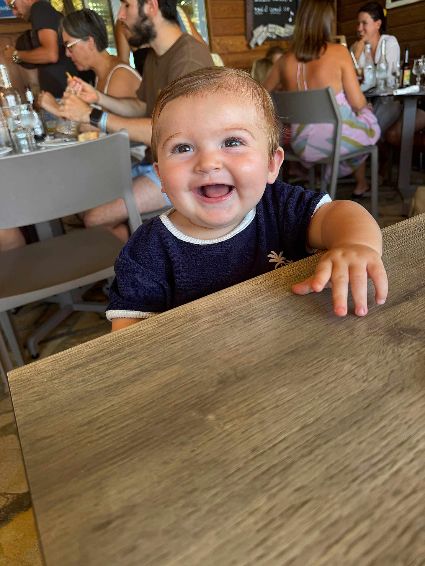 Andrea participe au concours pour gagner de l'argent avec cette photo : baby, smile, child, table, restaurant, people, happy, indoor, clothing, face, hand, wood, furniture, person, dining, background, group, casual, seat, light