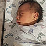 Luis Daniel Pulido is registered to the contest to win money with this photo: newborn, baby, infant, sleeping, swaddled, blanket, crib, nursery, portrait, face, closed_eyes, peaceful, indoors, resting, soft_lighting, sunlight, dinosaur_pattern, footprints, bedding, cozy