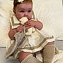 Dream is registered to the contest to win money with this photo: baby, child, plush_toy, blanket, dress, bow, socks, cushion, quilt, indoor, cute, portrait, soft_toy, knitwear, seated, infant, skin, face, hand, footwear