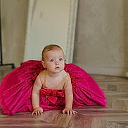 Elyse is registered to the contest to win money with this photo: baby, child, dress, pink, crawling, floor, wooden_floor, blue_eyes, mirror, indoor, curly_hair, sparkle, cute, adorable, person, portrait, flooring, young_child, curiosity, skin