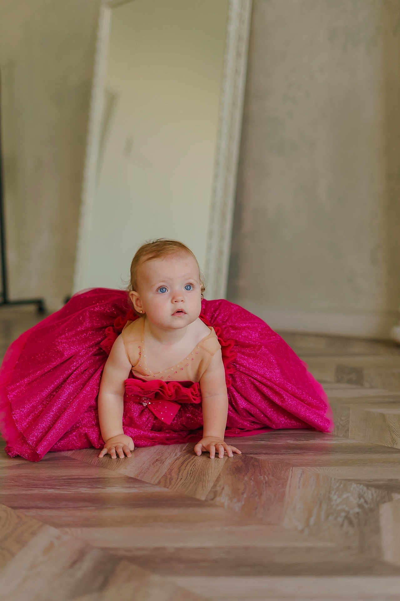 Elyse is registered to the contest to win money with this photo: baby, child, dress, pink, crawling, floor, wooden_floor, blue_eyes, mirror, indoor, curly_hair, sparkle, cute, adorable, person, portrait, flooring, young_child, curiosity, skin