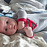 Elena a rejoint le concours — aidez-le/la à gagner de superbes lots ! baby, infant, onesie, superman_logo, bed, blanket, blue_eyes, cute, indoor, child, fist, clothing, soft_texture, lying_down, portrait, closeup, person, young, sleepwear, resting