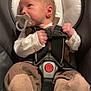 baby, newborn, infant, pacifier, car_seat, harness, buckle, socks, clothing, portrait, seated, head_support, hands, gaze, looking_up, soft_lighting, transport, safety_label, cozy, candid