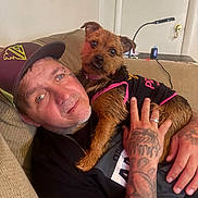 Haylee joined the competition — help win amazing prizes! black_clothing, brown_dog, cap, casual, couch, dog, face, furniture, hand, indoor, lamp, man, pet, relaxed, ring, small_dog, star_decoration, table, tattoo, wall