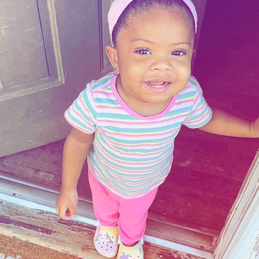 Genesis is registered to the contest to win money with this photo: baby, bodypart, clothing, door, doormat, face, footwear, happy, hat, head, mat, mouth, pants, person, photography, portrait, purple, shoe, smile, t_shirt