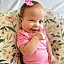 baby, bow, cheeky, child, cushion, cute, face, floral_pattern, happy, head, indoors, infant, one_person, person, pink_clothing, portrait, sitting, skin, small_arm, smile