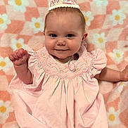 Adalie is registered to the contest to win money with this photo: adorable, baby, birthday_hat, blanket, celebration, cheerful, child, cute, face, festive, floral_pattern, happy, indoors, infant, pink_dress, portrait, sitting, smiling, soft_texture, young_child