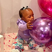 Zuri joined the competition — help win amazing prizes! baby, child, infant, sitting, balloons, birthday, party, purple_balloon, pink_balloon, floral_clothing, lavender_shirt, hair_bows, earring, smiling, portrait, indoor, playful, celebration, blanket, colorful