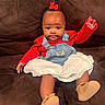 Zuri joined the competition — help win amazing prizes! baby, child, infant, portrait, sitting, couch, indoor, smiling, red_outfit, denim_overalls, bow, dress, shoes, fashion, happy, face, eyes, brown_couch, front_view, family_photo