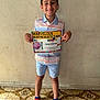 achievement, award, boy, celebration, certificate, child, clothing, floor, happy, indoor, person, red_socks, shirt, shorts, smile, socks, spiderman, standing, tiled_floor, wall