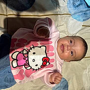 Yasmine a rejoint le concours — aidez-le/la à gagner de superbes lots ! baby, child, smiling, hello_kitty, pink_sweatshirt, blue_pants, blanket, indoor, cute, infant, portrait, happy, clothing, person, young_child, lying_down, face, head, skin, small_hands