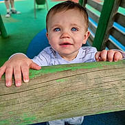 Vincent joined the competition — help win amazing prizes! child, toddler, baby, blue_eyes, hands, wood, playground, outdoor, clothing, person, face, smiling, curious, wooden_beam, shoes, fence, colorful, play_area, young_child, daylight