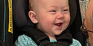 Markus is registered to the contest to win money with this photo: adult_hand, baby, bonding, car_seat, child, closeup, clothing, face, happy, head, indoor, infant, interaction, person, safety, seat, seatbelt, smiling, straps, watch