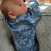 Weston is registered to the contest to win money with this photo: baby, infant, onesie, blue_clothing, snowflake_pattern, face, side_profile, soft_light, blanket, texture, indoors, bed, cute, child, resting, closeup, small_person, warm, peaceful, sleepwear