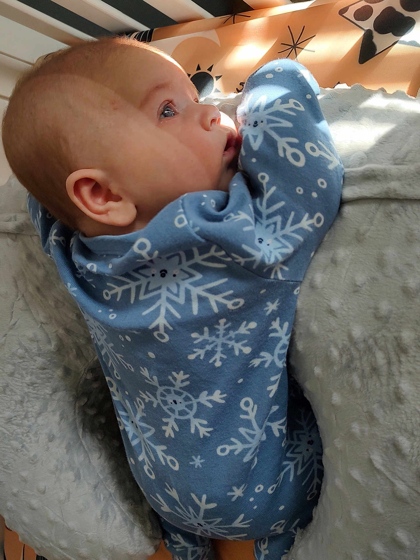 Weston is registered to the contest to win money with this photo: baby, infant, onesie, blue_clothing, snowflake_pattern, face, side_profile, soft_light, blanket, texture, indoors, bed, cute, child, resting, closeup, small_person, warm, peaceful, sleepwear