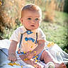 Weston is registered to the contest to win money with this photo: baby, child, outdoor, nature, grass, blanket, flower, yellow_flower, blue_eyes, sitting, cute, sunlight, summer, clothing, bowtie, suspenders, barefoot, portrait, infant, curious