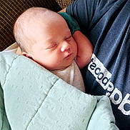 Quintin is registered to the contest to win money with this photo: baby, newborn, sleeping, blanket, person, arm, couch, clothing, portrait, resting, infant, comfort, cozy, indoor, head, face, peaceful, soft, toddler, closeup