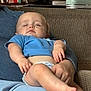 James joined the competition — help win amazing prizes! baby, sleeping, blue_shirt, diaper, couch, person, lap, hand, foot, indoors, books, stack, kettle, relaxation, comfort, home, furniture, skin, peaceful, child