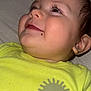 baby, smiling, face, yellow_shirt, sun_graphic, long_eyelashes, beauty_mark, close_up, cute, infant, child, portrait, soft_texture, happy, lying_down, skin, head, ear, hand, clothing