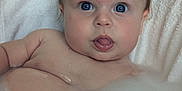 Violet is registered to the contest to win money with this photo: baby, bath, water, bubbles, towel, blue_eyes, tongue, skin, child, cute, infant, playful, wet, face, head, person, indoors, relaxing, young, expression