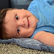 Isaac Tamayo joined the competition — help win amazing prizes! airplane, baby, blanket, blue_onesie, bracelet, car, carpet, cheeky, child, closeup, cute, face, hair, happy, indoors, infant, lying_down, skin, smiling, soft