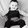baby, child, smiling, sitting, blanket, striped_clothing, overalls, happy, portrait, indoors, cute, face, head, person, infant, monochrome, black_and_white, sock, soft_texture, cozy