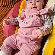 Agathe participe au concours pour gagner de l'argent avec cette photo : baby, bow, child, couch, cozy, cute, floral_shirt, happy, headband, home, indoor, infant, person, pillow, pink_overalls, portrait, relaxed, seated, smiling, socks